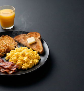 Desayuno americano con huevos, tocino, papas hash, pan tostado, café y jugo.