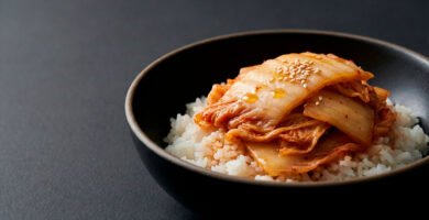 Bowl de arroz con kimchi suave, presentado en cerámica moderna sobre fondo negro con estilo editorial