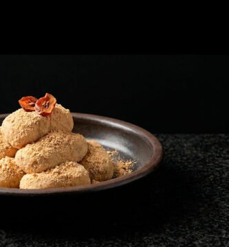 Injeolmi (인절미) Soft rice cakes coated in fine soybean powder, with a minimalist dried persimmon garnish.