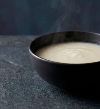 Juk base, gachas de arroz coreanas de textura suave y cremosa, servidas en bowl de cerámica sobre fondo negro editorial.