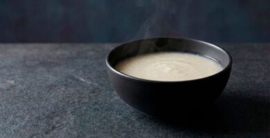 Juk base, gachas de arroz coreanas de textura suave y cremosa, servidas en bowl de cerámica sobre fondo negro editorial.