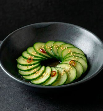 Banchan de pepino coreano (oi-muchim) servido en bowl de cerámica moderna sobre fondo negro