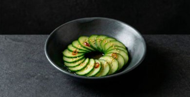 Banchan de pepino coreano (oi-muchim) servido en bowl de cerámica moderna sobre fondo negro